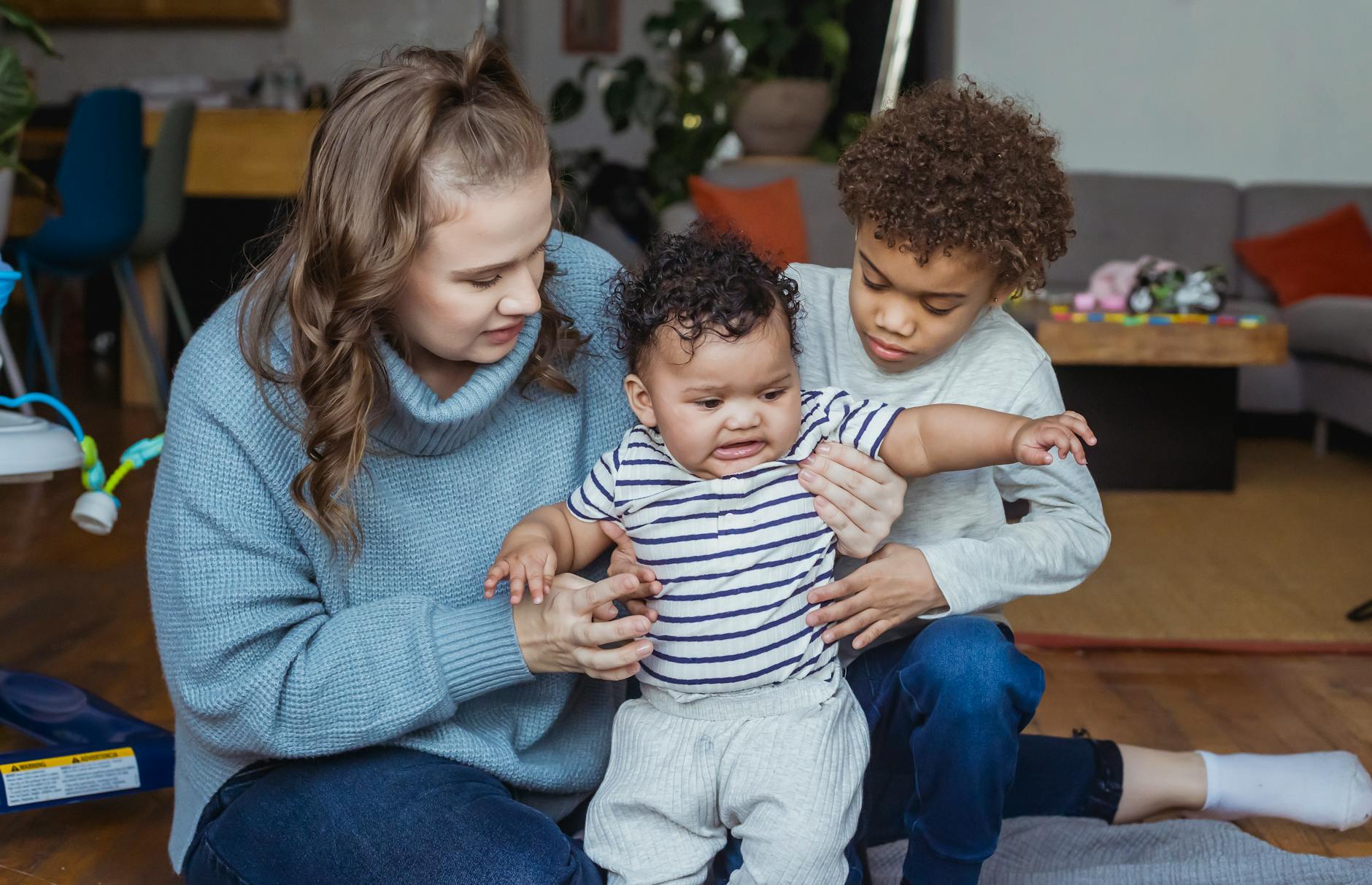 mother and elder son support baby under arms